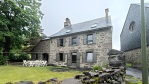 A stone building with multiple windows and a grassy yard.