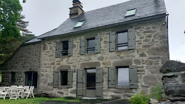 A stone building with multiple windows and a chimney.