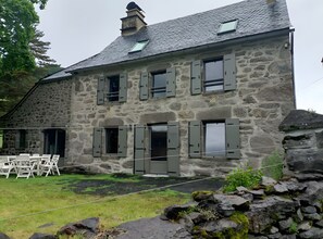 A stone building with multiple windows and a chimney. - Holiday Home “Gîte 9 Personnes Puy Mary” with Mountain View, Private Terrace and Garden (Le Claux)
