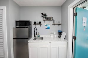 A compact kitchen with a refrigerator, microwave, and coffee maker. - 1915 Beach Club - Seaside Suite 8 (Daytona Beach)