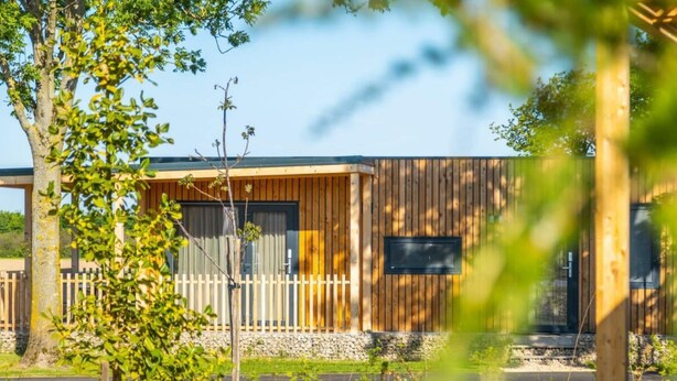 A wooden cabin with a stone foundation, a wooden fence, and a clear sky. - Holiday Home With 1 Bedroom (Berg en Terblijt)