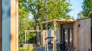 A wooden cabin with a covered patio, stone walls, and outdoor seating. - Holiday Home With 1 Bedroom (Berg en Terblijt)