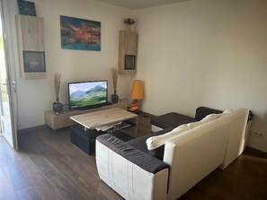 Ein Wohnzimmer mit Sofa, Fernseher, Lampe und einem Gemälde an der Wand.