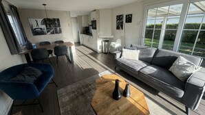 A modern living room with a sofa, coffee table, and dining area. - Holiday Home in Susteren With Terrace (Susteren)