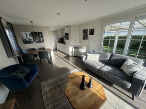 Een moderne woonkamer met een bank, salontafel en een eethoek.