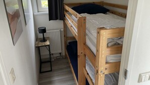 A bunk bed room with a desk, a radiator, and a window with curtains. - Holiday Home in Susteren With Terrace (Susteren)