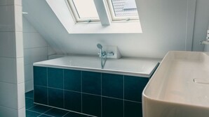 Un baño con tragaluz, bañera y ducha.