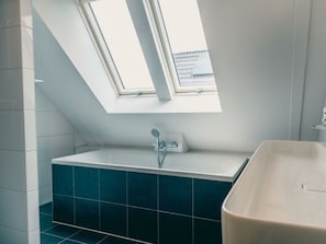 Ein Badezimmer mit Oberlicht, einer Badewanne und einer Dusche.