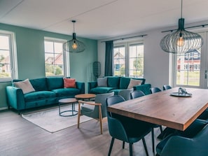 Ein modernes Wohnzimmer mit einem Ecksofa, einem Holzesstisch und Pendelleuchten.