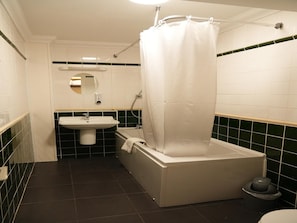 Ein Badezimmer mit weißem Waschbecken, einer Badewanne, einer Duschvorhang, einer Toilette und einem Spiegel.