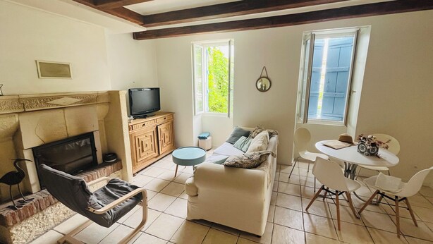 Een woonkamer met een open haard, televisie, bank en een eethoek.