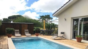 A rectangular swimming pool with a wooden deck, lounge chairs, and a covered outdoor seating area. - HOUSE IN THE MEYRAN NEIGHBORHOOD NEAR LA HUME (Gujan-Mestras)
