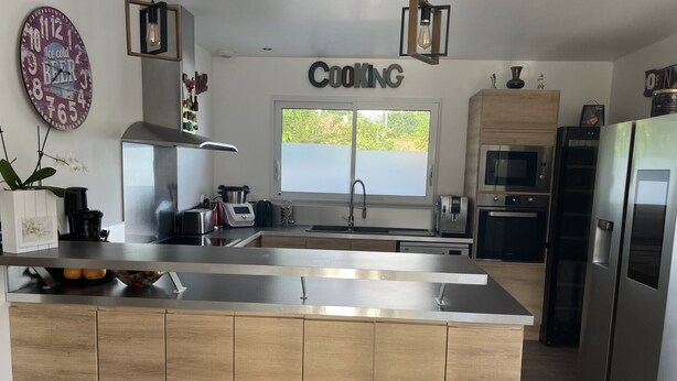 A modern kitchen with a central island, stainless steel appliances, and a large window. - HOUSE IN THE MEYRAN NEIGHBORHOOD NEAR LA HUME (Gujan-Mestras)