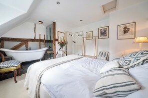 A bedroom with a large bed, a bathtub, a wooden ladder, and a mirror. - Windmill Cottage Sleeps 4 With Enclosed Garden (Henley-on-Thames)