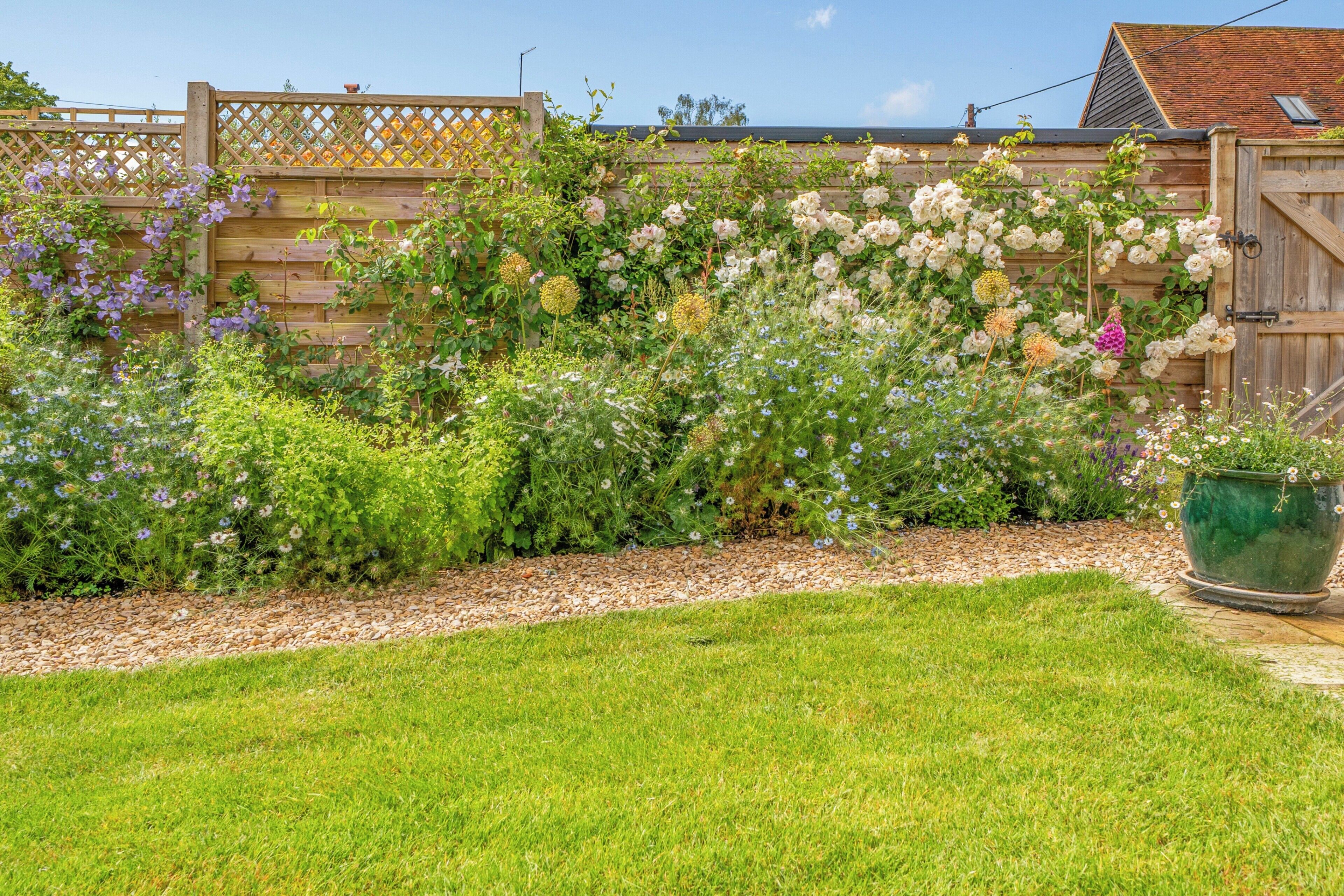 A garden with a wooden fence, a pathway, and a green pot.