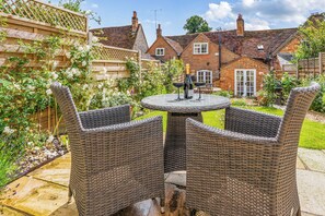 A garden patio with wicker chairs and a table, surrounded by a brick house and lush greenery. - Windmill Cottage Sleeps 4 With Enclosed Garden (Henley-on-Thames)