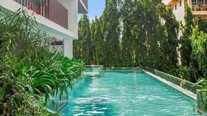 A swimming pool surrounded by lush greenery and modern buildings. - Solaris Luxury Residence | Osu • Pool • Gym (Accra)