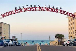 Straßenansicht mit einem Schild, das 'Daytona Beach World's Most Famous Beach' zeigt.
