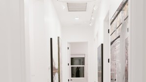 Un couloir aux murs blancs, doté d’un plancher en bois et orné d’œuvres d’art encadrées.