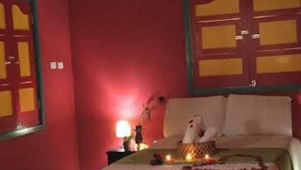 Um quarto com cama, mesa de cabeceira e uma parede com painel decorativo.