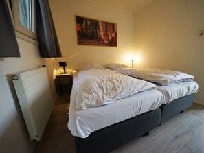 Ein Schlafzimmer mit einem Bett, einem Nachttisch, einer Lampe, einem Heizkörper und einem Bild an der Wand.