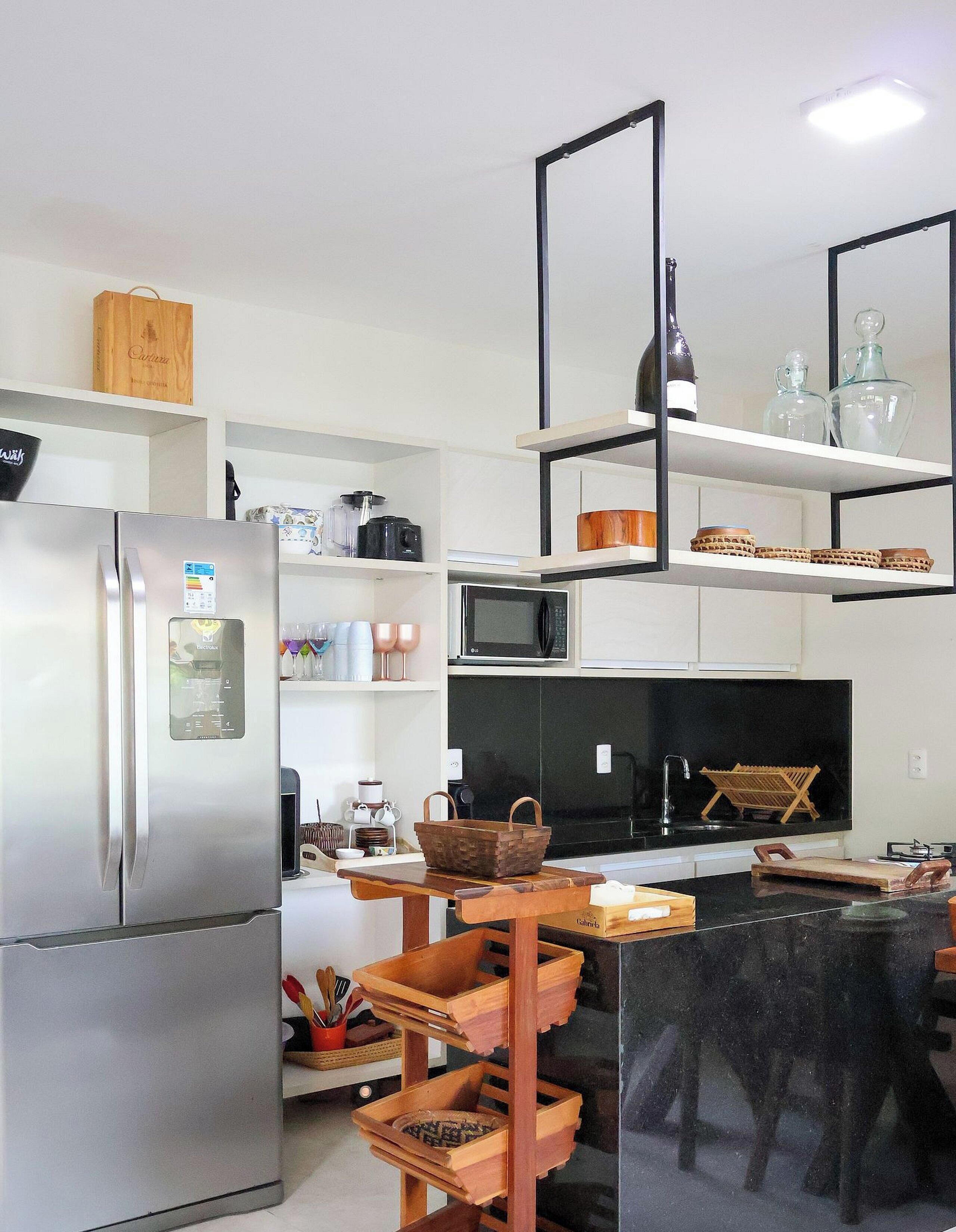 Una cocina moderna con un refrigerador de acero inoxidable, microondas y una mesa de comedor de madera con sillas.