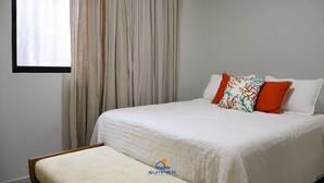 A bed with white bedding, a bench, and a window with curtains. - Condominio Fontes da Pipa (Tibau do Sul)