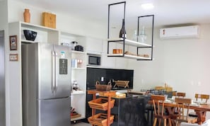 Eine moderne Küche mit Kühlschrank, Mikrowelle und Essbereich mit Holztischen und einem Tisch.