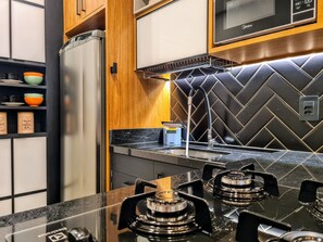 Een moderne keuken met een zwart, taps gelegd achterwandpaneel, een inbouwoven, een gasfornuis en een magnetron.