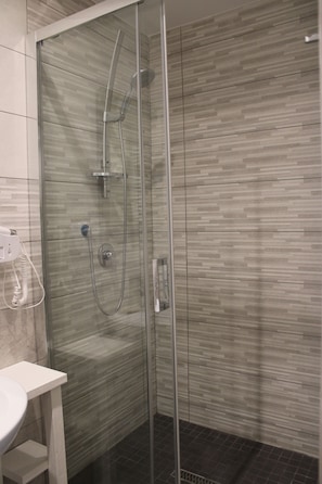 A modern bathroom with a glass-enclosed shower, a white sink, and tiled walls. - Mimmù (Naples)