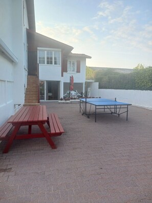 Ein Außenbereich mit einer Terrasse, einem Tischtennisplatten und einem Picknicktisch.