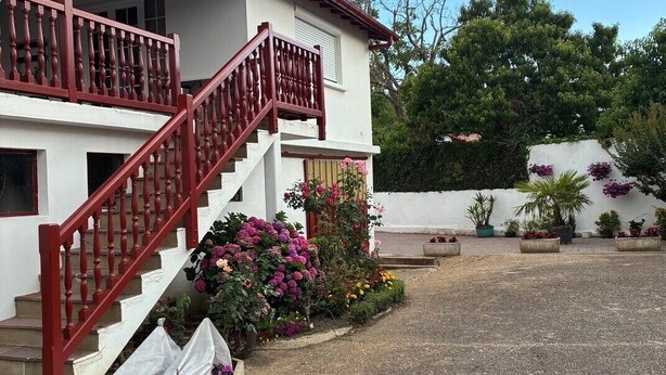A two-story building with a red staircase and a white exterior. - Apartment for rent in the Basque Country near the beaches of Biarritz and the mountains (USTARITZ)