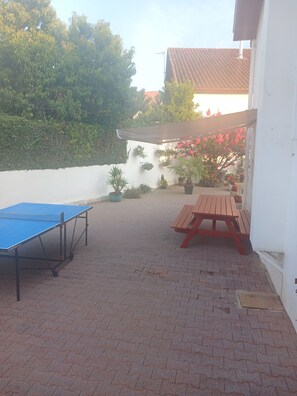 An outdoor patio area with a ping pong table, a wooden bench, and potted plants. - Apartment for rent in the Basque Country near the beaches of Biarritz and the mountains (USTARITZ)