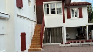 A two-story house with a staircase leading to the upper floor, a garage, and a paved driveway. - Apartment for rent in the Basque Country near the beaches of Biarritz and the mountains (USTARITZ)