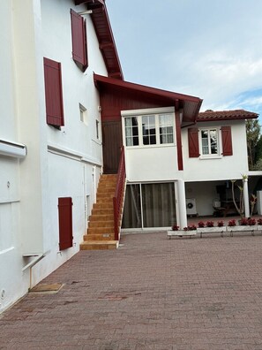 Ein zweistöckiges Haus mit einer Treppe zum Obergeschoss, einer Garage und einem gepflasterten Auffahrt.
