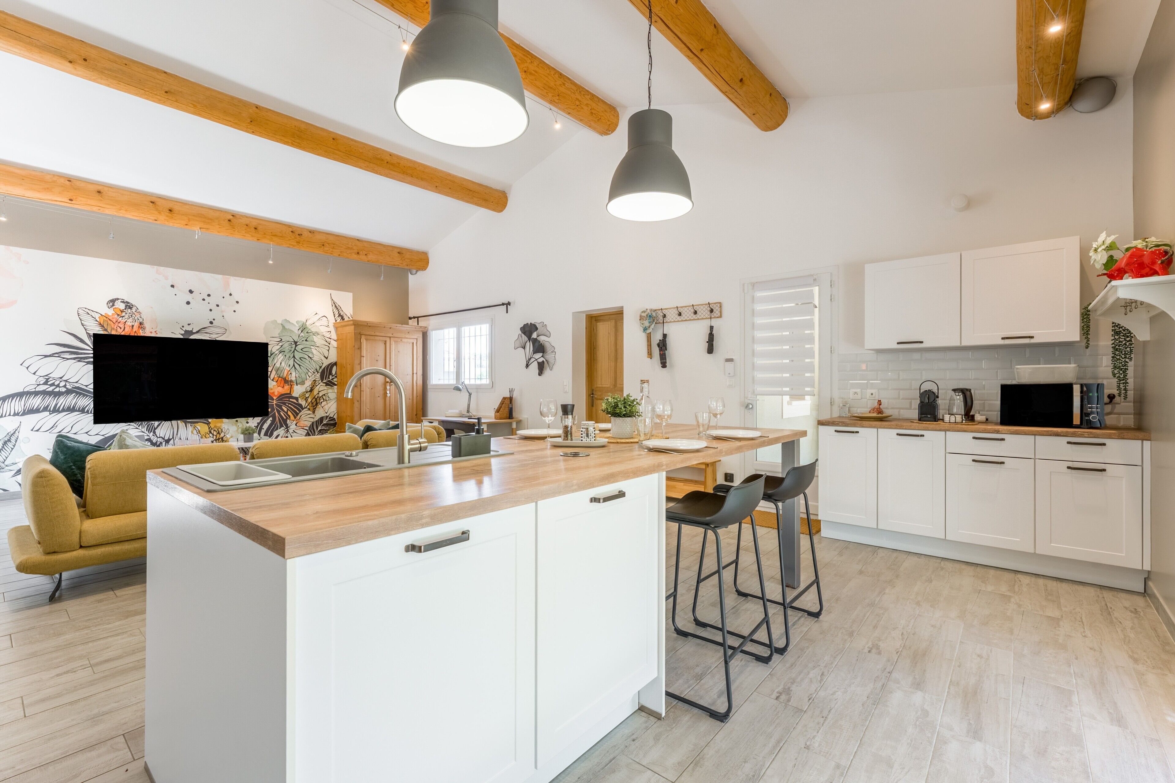 Une cuisine moderne dotée d’un îlot central, de meubles blancs et d’un éclairage suspendu.