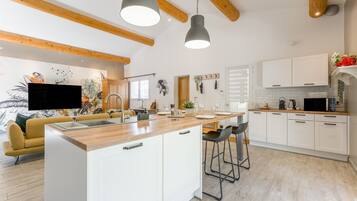 Une cuisine moderne dotée d’un îlot central, de meubles blancs et d’un éclairage suspendu.