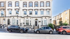 A row of terraced houses with a front entrance, a staircase, and a sign indicating the house number.