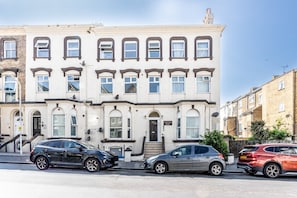 A row of terraced houses with a front entrance, a staircase, and a sign indicating the house number.