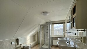 Un baño moderno con ducha, inodoro y dos lavabos.