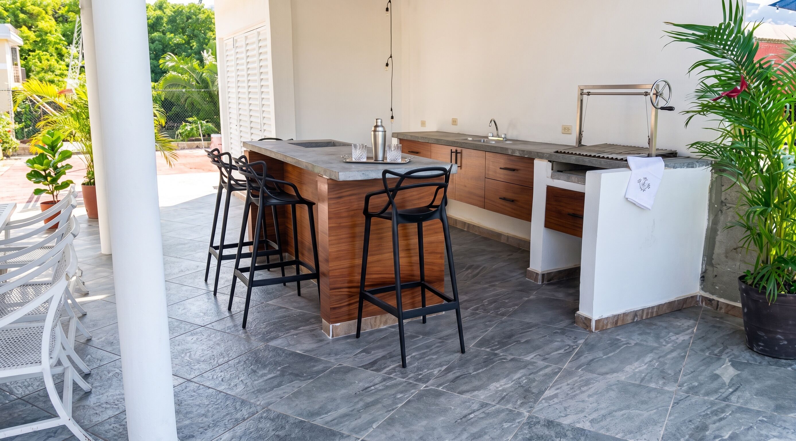 Una cocina con barra, dos taburetes, un fregadero y una planta en maceta.
