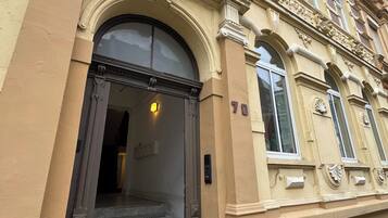 Ein Gebäude mit einem großen Bogenportal, einer Treppe, die zum Eingang führt, und der Hausnummer 70 an der Fassade.