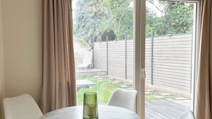 En matplats med ett runt bord, fyra vita stolar och en vas av glas.
