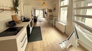 Ett modernt kök med en central köksö, en matplats med barstolar och ett stort fönster som släpper in naturligt ljus.