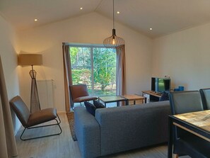 A modern living room with a sofa, armchair, and a TV. - Holiday Home in Otterlo With Terrace (Otterlo)
