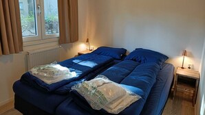 Un dormitorio con dos camas, una ventana con cortinas, un radiador y lámparas de noche.