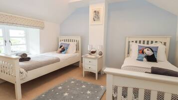 A bedroom with two single beds, a nightstand, a window, and a star-patterned rug.