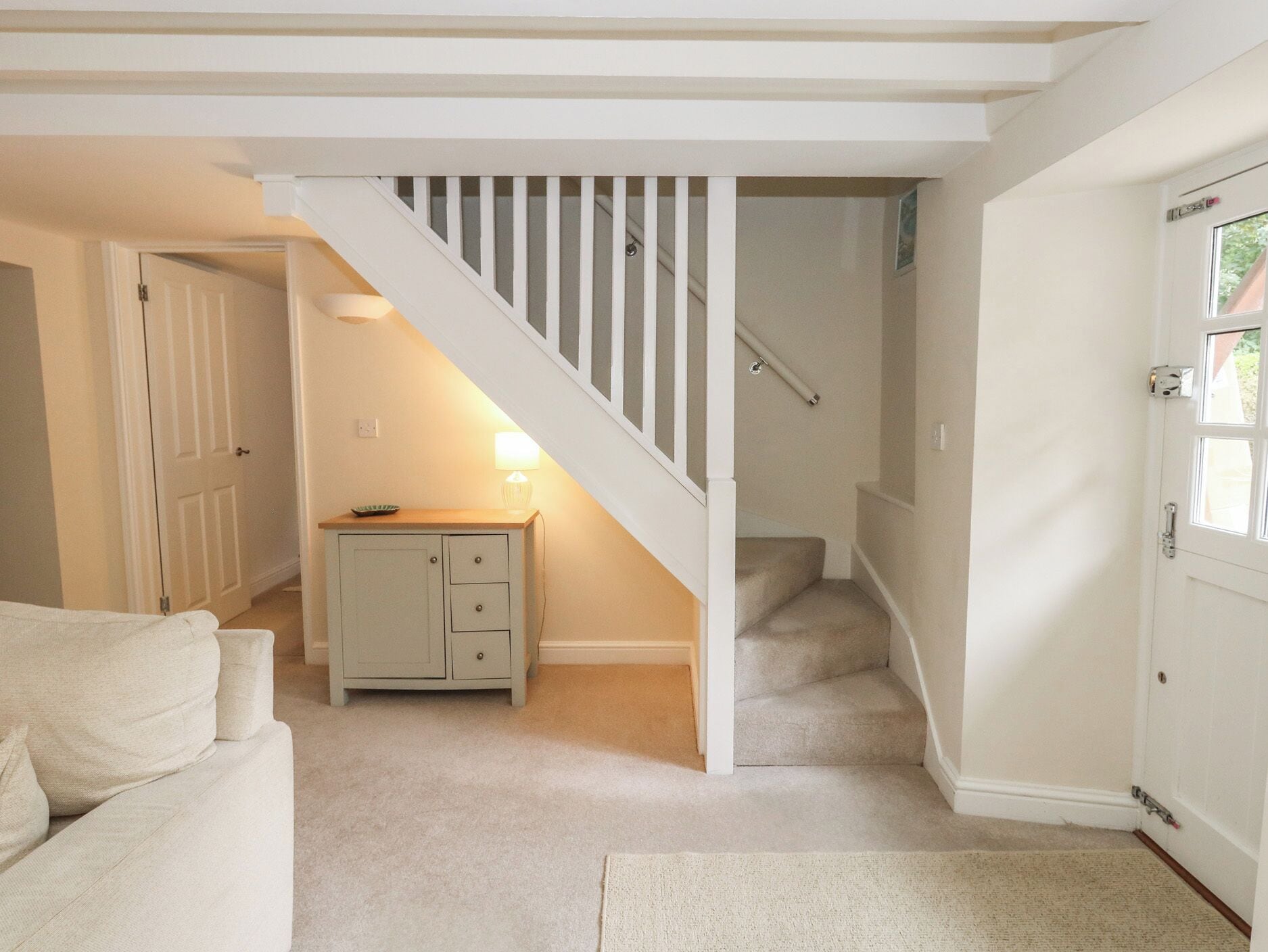 Ein Flur mit Treppe, einer Tür, einem kleinen Schrank und einer Lampe.