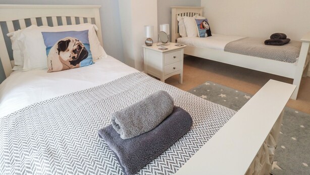 Een hotelkamer met twee bedden, een nachtkastje met een lamp, een klein nachtkastje met een spiegel en een aan de muur hangend schilderij.
