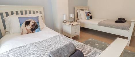 Une chambre d’hôtel avec deux lits, une table de chevet avec une lampe, une petite table de chevet avec un miroir et un tableau accroché au mur.